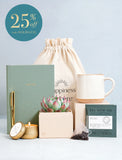 Workspace gift set featuring a sage green notebook, gold pen, succulent, speckled ceramic mug, candle, and tea in a canvas bag. - Image 