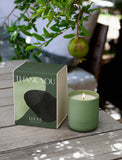 Thank You Candle in a sage green ceramic jar next to a matching decorative box on a rustic wooden table. - Image 