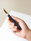 Hand holding a black pen. - Image 