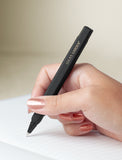Hand holding pen and writing in journal. - Image 