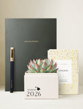 Succulent in gift box in front of notebook and pen. - Image 